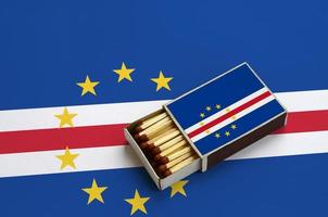 Cabo verde flag is shown in an open matchbox, which is filled with matches and lies on a large flag photo