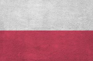 Poland flag depicted in bright paint colors on old relief plastering wall. Textured banner on rough background photo