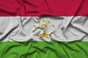 Tajikistan flag is depicted on a sports cloth fabric with many folds. Sport team banner photo