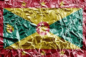 Grenada flag depicted in paint colors on shiny crumpled aluminium foil closeup. Textured banner on rough background photo