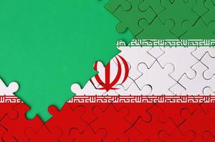 Iran flag is depicted on a completed jigsaw puzzle with free green copy space on the left side photo
