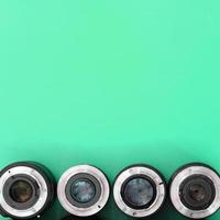 Several photographic lenses lie on a bright turquoise background. Copy space photo