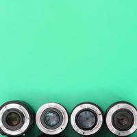 Several photographic lenses lie on a bright turquoise background. Copy space photo