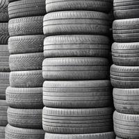 Old used tires stacked with high piles in secondary car parts shop garage photo