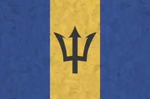 Barbados flag depicted in bright paint colors on old relief plastering wall. Textured banner on rough background photo