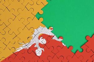 Bhutan flag is depicted on a completed jigsaw puzzle with free green copy space on the right side photo