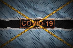 Botswana flag and Covid-19 stamp with orange quarantine border tape cross. Coronavirus or 2019-nCov virus concept photo