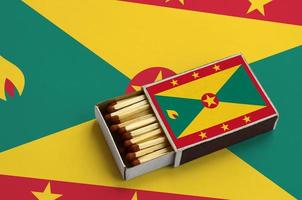 Grenada flag is shown in an open matchbox, which is filled with matches and lies on a large flag photo