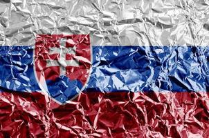 Slovakia flag depicted in paint colors on shiny crumpled aluminium foil closeup. Textured banner on rough background photo