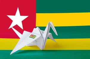 Togo flag depicted on paper origami crane wing. Handmade arts concept photo