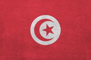 Tunisia flag depicted in bright paint colors on old relief plastering wall. Textured banner on rough background photo