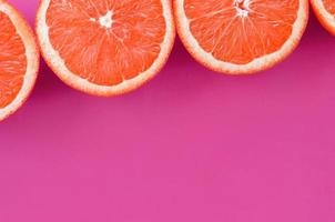 Top view of a several grapefruit slices on bright background in purple color. A saturated citrus texture image photo