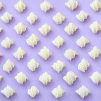 Colorful marshmallow laid out on violet paper background. pastel creative textured pattern. minimal photo