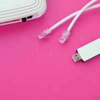 Internet router, portable USB wi-fi adapter and internet cable plugs lie on a bright pink background. Items required for internet photo