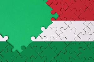 Hungary flag is depicted on a completed jigsaw puzzle with free green copy space on the left side photo