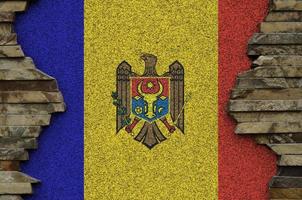 Moldova flag depicted in paint colors on old stone wall closeup. Textured banner on rock wall background photo