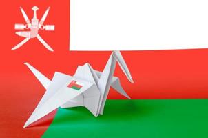 Oman flag depicted on paper origami crane wing. Handmade arts concept photo