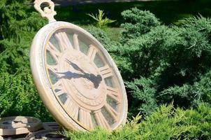 Street clock in a park under branches of trees close up photo