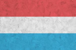 Luxembourg flag depicted in bright paint colors on old relief plastering wall. Textured banner on rough background photo