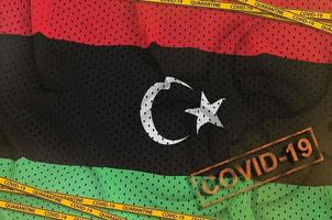 Libya flag and Covid-19 biohazard symbol with quarantine orange tape and stamp. Coronavirus or 2019-nCov virus concept photo