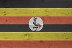 Uganda flag depicted in bright paint colors on old wooden wall. Textured banner on rough background photo