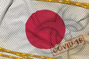 Japan flag and Covid-19 biohazard symbol with quarantine orange tape and stamp. Coronavirus or 2019-nCov virus concept photo