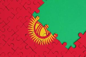 Kyrgyzstan flag is depicted on a completed jigsaw puzzle with free green copy space on the right side photo