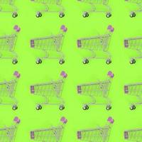 Shopping addiction, shopping lover or shopaholic concept. Many small empty shopping carts perform a pattern on a pastel colored paper background. Flat lay composition, top view photo