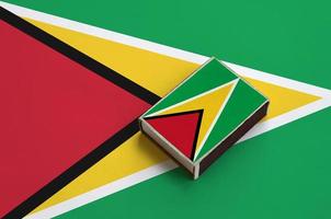 Guyana flag is pictured on a matchbox that lies on a large flag photo