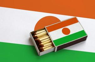 Niger flag is shown in an open matchbox, which is filled with matches and lies on a large flag photo