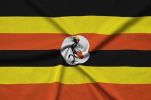 Uganda flag is depicted on a sports cloth fabric with many folds. Sport team banner photo
