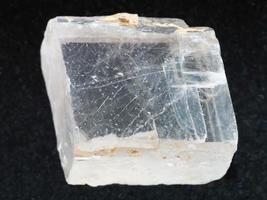 rough crystal of Iceland spar gemstone on dark photo