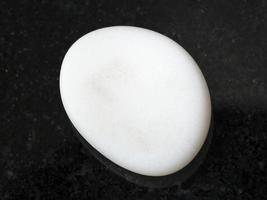 tumbled cacholong white opal gemstone on dark photo