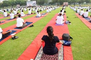 New Delhi, India, June 21 2022 - Group Yoga exercise session for people at Yamuna Sports Complex in Delhi on International Yoga Day, Big group of adults attending yoga class in cricket stadium photo