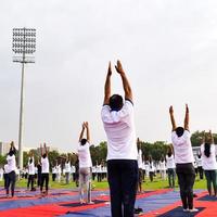 New Delhi, India, June 21 2022 - Group Yoga exercise session for people at Yamuna Sports Complex in Delhi on International Yoga Day, Big group of adults attending yoga class in cricket stadium photo