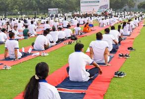 New Delhi, India, June 21 2022 - Group Yoga exercise session for people at Yamuna Sports Complex in Delhi on International Yoga Day, Big group of adults attending yoga class in cricket stadium photo