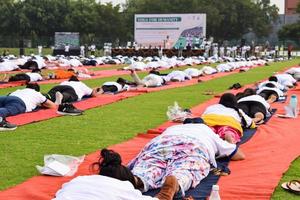 New Delhi, India, June 21 2022 - Group Yoga exercise session for people at Yamuna Sports Complex in Delhi on International Yoga Day, Big group of adults attending yoga class in cricket stadium photo