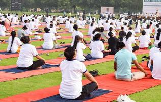 New Delhi, India, June 21 2022 - Group Yoga exercise session for people at Yamuna Sports Complex in Delhi on International Yoga Day, Big group of adults attending yoga class in cricket stadium photo