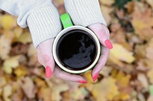 mujer con suéter blanco sosteniendo una taza de café verde foto