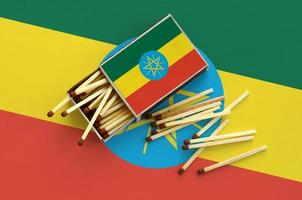 Ethiopia flag is shown on an open matchbox, from which several matches fall and lies on a large flag photo