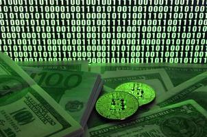 Two bitcoins lies on a pile of dollar bills on the background of a monitor depicting a binary code of bright green zeros and one units on a black background. Low key lighting photo