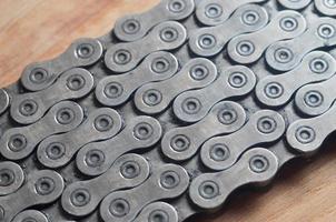 Dirty and oily chain from a mountain bike lying on a wooden table in a bicycle shop photo