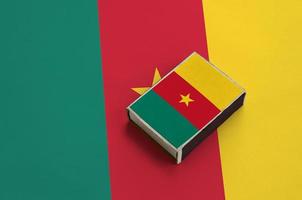 Cameroon flag is pictured on a matchbox that lies on a large flag photo