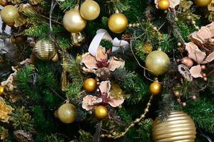 Decorating Christmas tree close up. Decoration bulb, green fir tree, golden x-mas toys and lights. Use for Christmas and New years celebration background photo