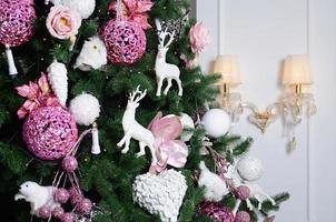 Decorating Christmas tree close up. Decoration bulb, fir tree, pink x-mas toys and lights. Use for Christmas and New years celebration background photo