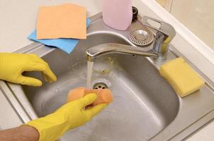 Person or householder cleaning the kitchen sink with sponge in close up view photo