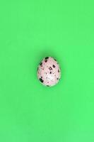 One quail egg on a light green surface, top view, empty place fo photo