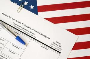 I-360 Petition for Amerasian, Widower or special immigrant blank form lies on United States flag with blue pen from Department of Homeland Security photo