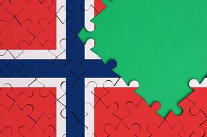 Norway flag is depicted on a completed jigsaw puzzle with free green copy space on the right side photo
