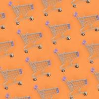 Shopping addiction, shopping lover or shopaholic concept. Many small empty shopping carts perform a pattern on a pastel colored paper background. Flat lay composition, top view photo